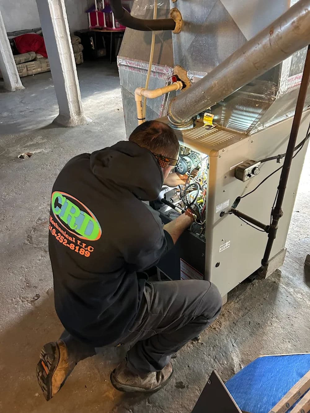 Technician servicing a furnace in a basement, ensuring optimal heating performance.