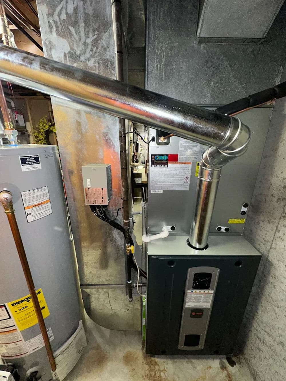 Modern furnace and water heater installation in a basement utility room.