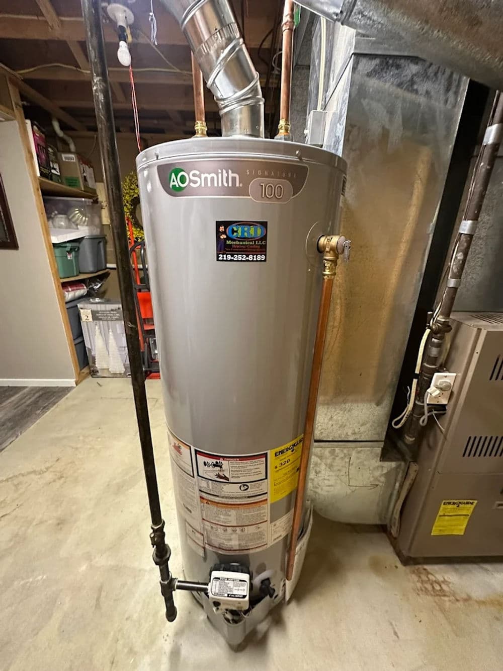 A.O. Smith water heater model 100 in a basement, featuring copper pipes and installation details.